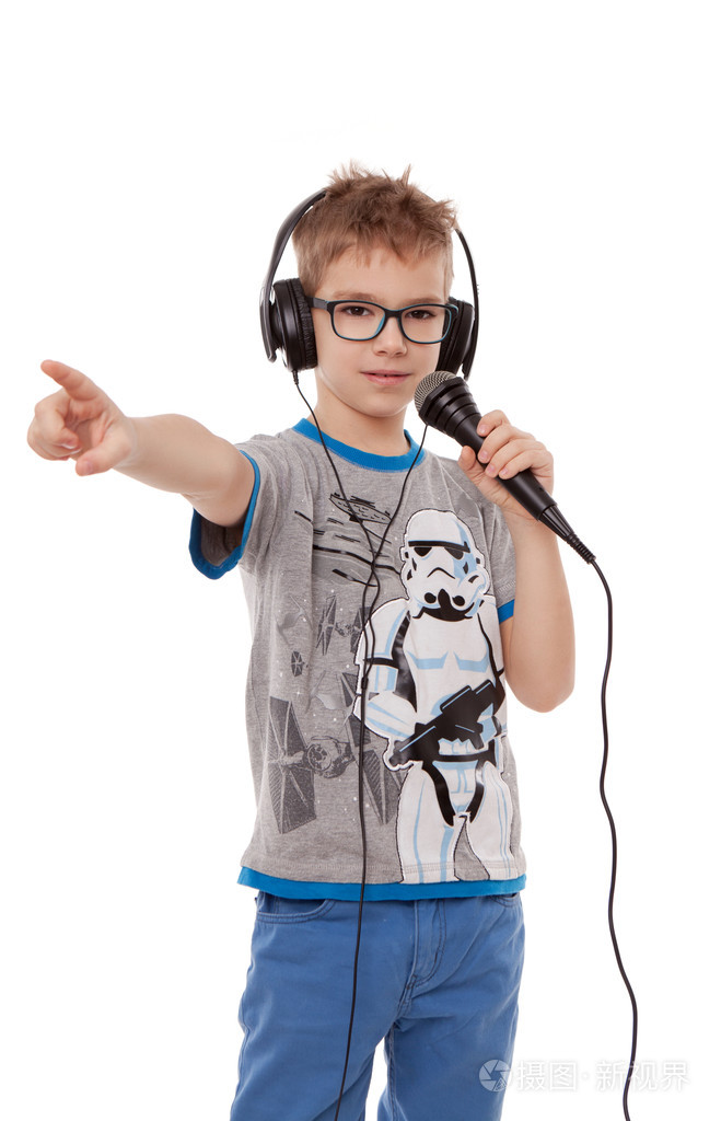戴着耳机的男孩对着白b上的麦克风唱歌