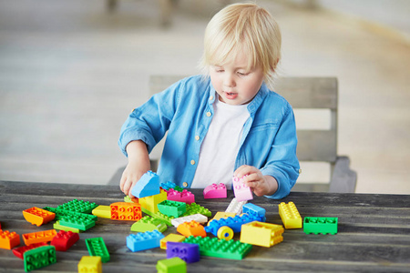 小男孩玩彩色塑料建筑积木照片