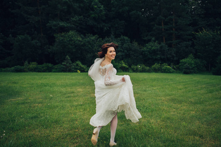 美丽的白种新娘在绿色公园奔跑照片