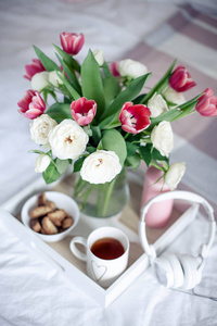 浪漫的早餐在床上。花的花束。玫瑰和郁金香。春天.情人节国际妇女节。舒适
