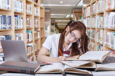 可爱的学生在图书馆里写书