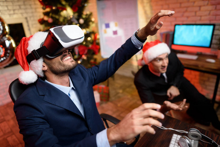 生意人在新年前夕在办公室。它有一个虚拟现实的头盔。他玩游戏