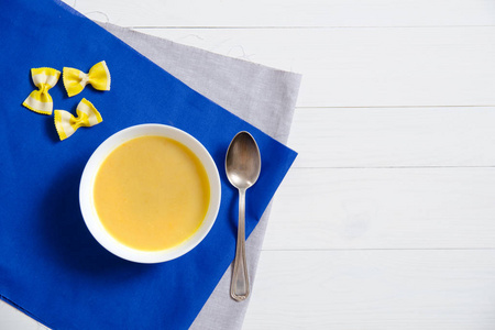 奶油汤用蝴蝶糊在白色盘子里用银色勺子在亚麻餐巾上
