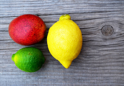 黄色和红色水果新鲜成熟有机芒果, 柠檬和酸橙旧木制的桌子上.