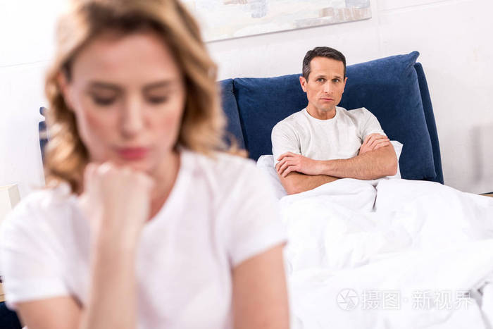 选择焦点的心烦妇女坐在床上与丈夫背后的家庭, 关系困难的概念