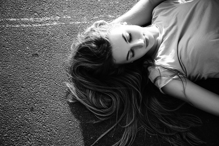躺在沥青上的漂亮女孩。 黑白的
