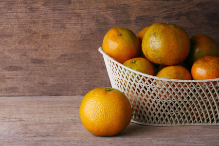 在木桌背景上的白色篮子橙色水果