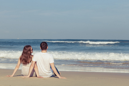 恩爱夫妻坐在沙滩上，在白天的时间
