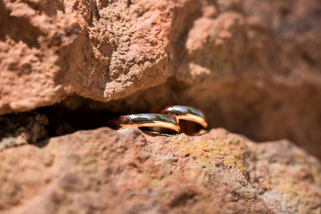 两个金色的结婚戒指在岩石的裂缝，结婚戒指背景概念