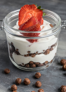 水果酸奶杯美味的白色酸奶在玻璃杯里用巧克力球, 水果和燕麦粥照片