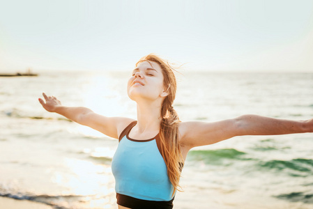 健身运动模型快乐的笑出在日出的户外工作期间做练习。美丽白种女性外海边上午训练，