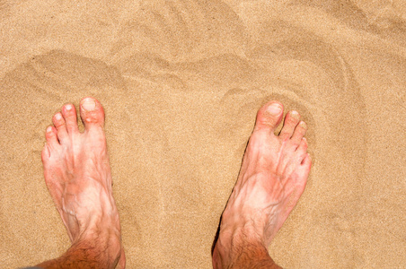男性的脚在沙滩上