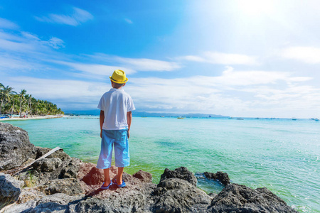 在热带海洋沙滩上玩耍的男孩。孩子在家庭海度假期间