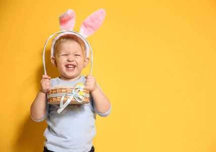 可爱的小男孩与兔子耳朵举行篮子充满复活节彩蛋的颜色背景