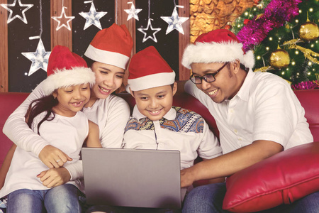 圣诞节时使用笔记本电脑的快乐家庭