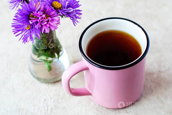 红茶上浅色的背景和紫色花粉红色大杯