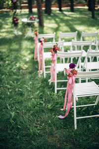 户外婚礼仪式, 用鲜花和丝带装饰的椅子站在草地上排成一行