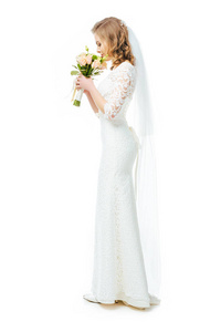 有吸引力的新娘在婚纱礼服和面纱的侧面, 在白色的鲜花隔离的花束