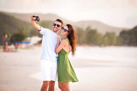 幸福的新婚夫妇蜜月度假和白色海滩拍照