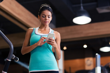 在健身房中使用智能手机的女人
