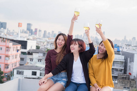 亚洲朋友组在顶部屋顶饮酒和有乐趣的户外欢呼