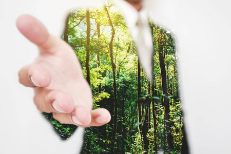 双曝光, 商人伸手与林中的绿树握手。环保和可持续的商业