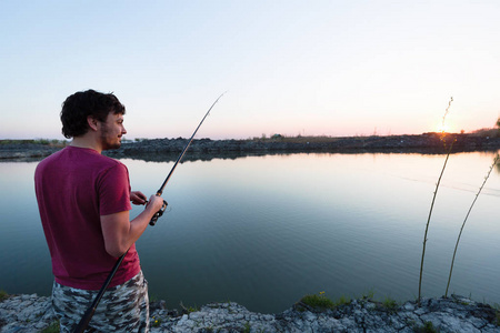 年轻人在池塘和享受的爱好钓鱼