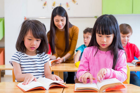 两个亚洲女孩孩子读书教室，同时老师 t