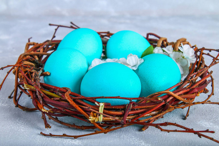 蓝色的复活节彩蛋在一个灰色的混凝土背景白色的花朵巢