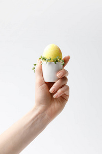 女性持有黄色彩绘复活节彩蛋的图像被隔离在白色的蛋架上