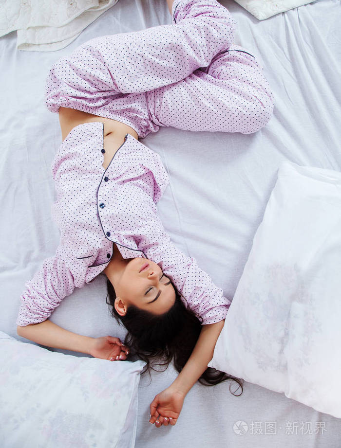 女孩在家睡在一张白色的床上睡在睡衣上的年轻女子在家里的白色亚麻布