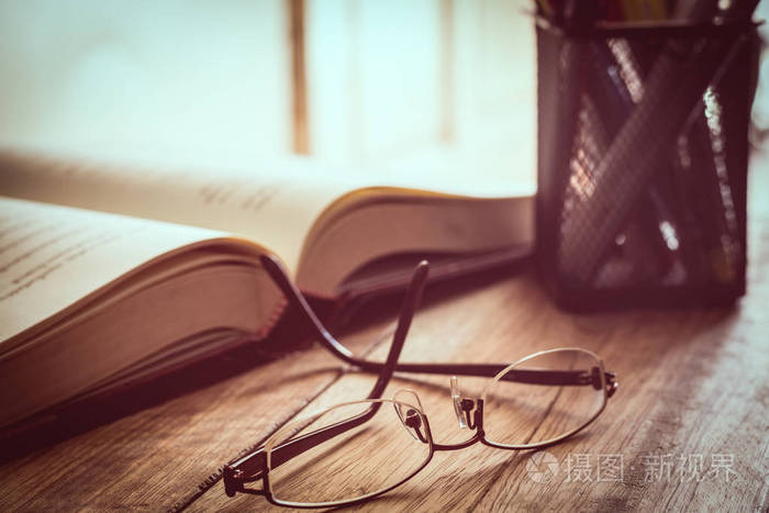 木桌上的眼镜,书和书写材料
