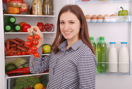 年轻漂亮的女孩附近健康食物在冰箱里