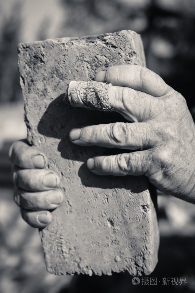 老人的两只手握着萼片上的旧砖