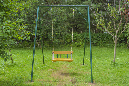 孩子们在绿树成荫的背景下荡秋千照片