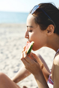 年轻美丽的妇女在海滩吃西瓜图片