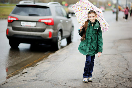 孩子的女孩用伞走在城市的街道