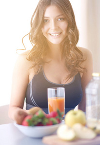 女孩坐在厨房的桌子上的水果和果汁的眼镜