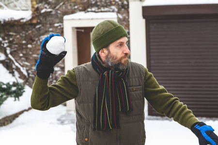 戴着胡子的男人在院子里扔雪球