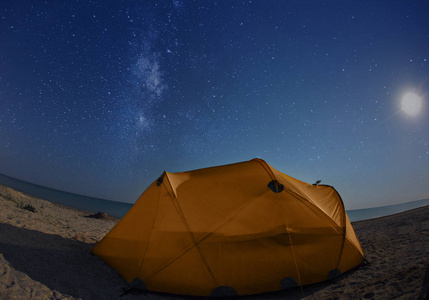 海滩上的橙色帐篷在星空下的夜晚照片