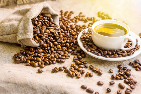 热咖啡杯和烤咖啡豆在木桌上。早上好咖啡咖啡豆深色背景