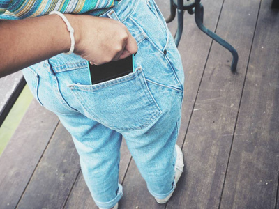 女性手持智能手机在牛仔裤口袋里的特写