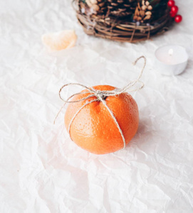 白色圣诞冬季背景。橘子与丝带在白色背景与蜡烛。新年圣诞节节日背景。纹理空间。贺卡
