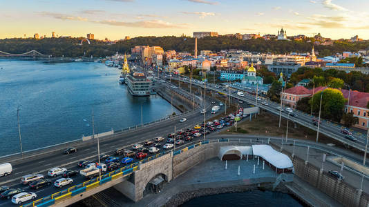 鸟瞰第聂伯河河和 Podol 区天际线从上面, 交通堵塞在路, 日落在基辅 基辅 城市, 乌克兰
