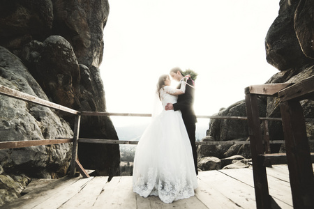 新婚夫妇在爱接吻和拥抱附近岩石上亮丽的风景线