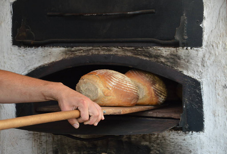 新鲜出炉的面包从一个古老的老式木烧制烤箱照片