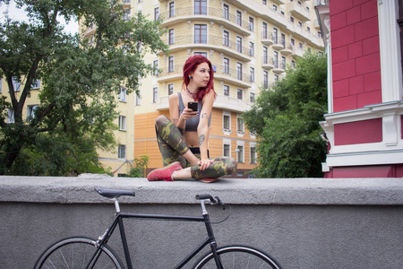 早晨自行车骑年轻的妇女与红色头发, 运动的女性与黑色自行车在公园