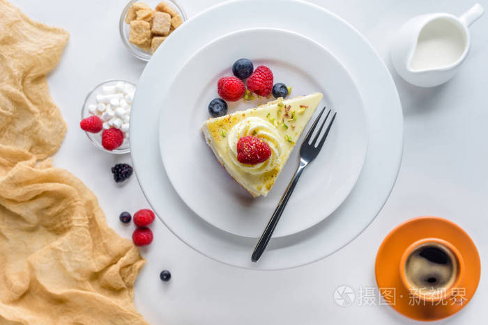 白色桌上有浆果的一块蛋糕的顶部视图