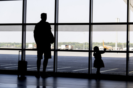 男人和女孩剪影看飞机降落在机场