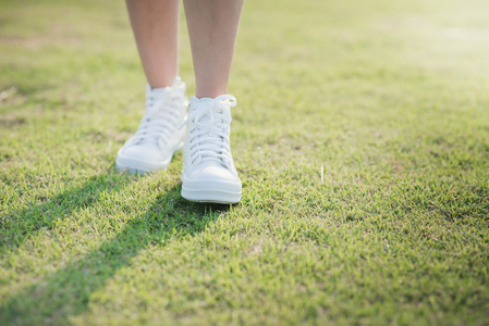 走运动鞋走在阳光下的白色运动鞋的女人照片